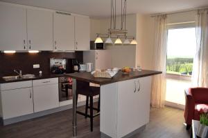 a kitchen with white cabinets and a black counter top at Fehmarnstrand 78 App 10 in Staberdorf
