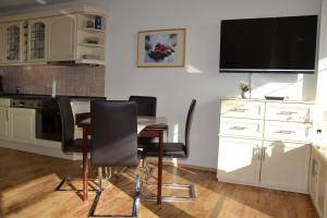 Il comprend une cuisine avec une table et des chaises ainsi qu'une télévision à écran plat. dans l'établissement Traumblick FeWo Nr 459, à Sierksdorf