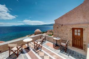 un patio con mesas y sillas con vistas al océano en Malvasia Traditional Hotel, en Monemvasia