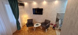 a living room with two chairs and a table and a tv at OLIVERA APARTMENT in Belgrade