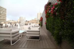 uma varanda com cadeiras brancas e flores num edifício em Eyal Hotel by Smart Hotels em Jerusalém
