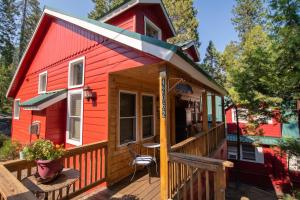 a red tiny house with a deck with a table at Elliott House Boutique Inn in Shaver Lake
