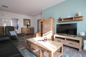 een woonkamer met een grote televisie en een tafel bij Atempause Greetsiel in Krummhörn
