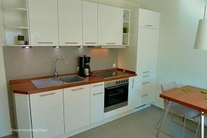 Villa Morgentied, FW 2 في زنغست: مطبخ بدولاب بيضاء ومغسلة وطاولة