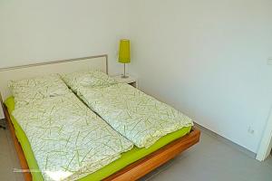 Villa Morgentied, FW 2 في زنغست: سرير في غرفة مع مصباح أصفر على طاولة
