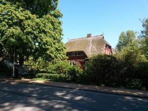 una casa con techo de paja al lado de una carretera en Ferienwohnung "Achtern Diek", en Prerow