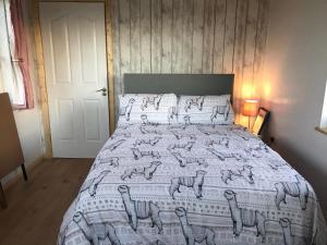 Un dormitorio con una cama con una manta con animales. en The Beautiful Lazy Llama Shepherd Hut Farm Stay en Ballyshannon