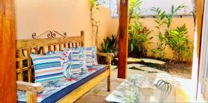 a porch with a bench with pillows and a table at Casa com lazer a 2 minutos da Praia de Juquehy in São Sebastião