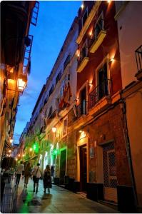 a group of people walking down a street at night at Hostal San Francisco in Cádiz