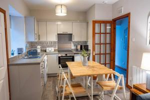 una cocina con mesa de madera y sillas. en Cozy Newly Renovated Town Centre Apartment, en Aberfeldy