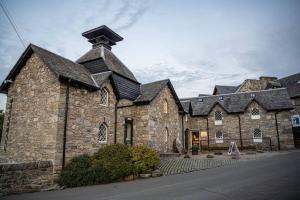 a large stone building with a black roof at Cozy Newly Renovated Town Centre Apartment in Aberfeldy