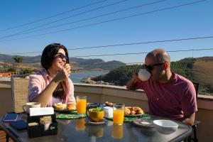 Ein Mann und eine Frau sitzen am Tisch und essen Frühstück. in der Unterkunft Pousada Quintal da Lua in Capitólio