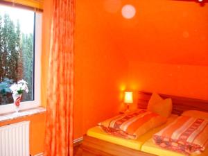 Habitación naranja con 2 camas y ventana en Ferienwohnung Riek, en Büdelsdorf