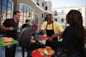 un gruppo di persone che preparano il cibo su una griglia di Staybridge Suites Phoenix Glendale Sports Dist, an IHG Hotel a Glendale