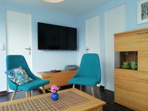 a living room with two blue chairs and a tv at Kleiner Bungalow im Grünen in Radeberg