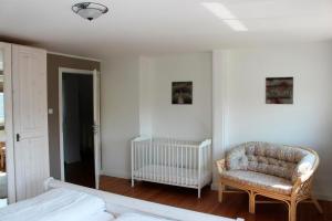 um quarto com uma cama, uma cadeira e um berço em Zollhaus Strukkamp em Strukkamp auf Fehmarn
