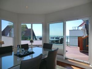 uma sala de jantar com mesa, cadeiras e janelas em Luxus-Penthouse am Strand, mit Traum-Meerblick, Dachterrasse und Sauna em Wyk auf Föhr