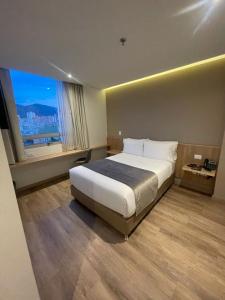 a bedroom with a large bed and a large window at EM Budget Hotel Corferias Embajada Americana in Bogotá