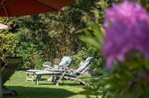zwei Stühle und ein Tisch und ein Regenschirm im Gras in der Unterkunft Dörphuus Wohnung Dorfblick in Spiekeroog