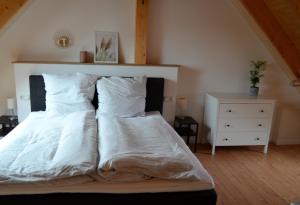 un letto con lenzuola e cuscini bianchi in una camera da letto di Maritime Ferienwohnung auf Gut Bennewohld KP a Heide