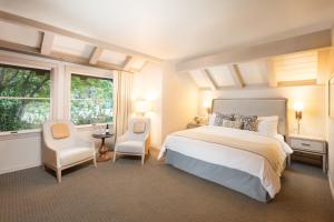 a bedroom with a bed and two chairs and a window at Harvest Inn in St. Helena