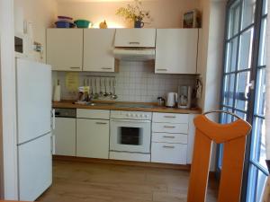 プレローにあるEichenpark 34のキッチン(白いキャビネット、オレンジの椅子付)