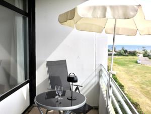 a balcony with a table and an umbrella at Strandbude Fehmarn in Fehmarn