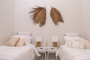 two beds in a room with white walls at Corlette Shores. Dreamy Beachside Holiday Home. in Corlette