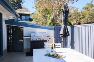 um pátio com uma mesa e um guarda-chuva e uma cozinha em Corlette Shores. Dreamy Beachside Holiday Home. em Corlette