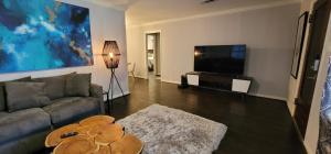 a living room with a couch and a flat screen tv at The Harby Street House - Close to U of H, Stadiums, Downtown, Med Center in Houston