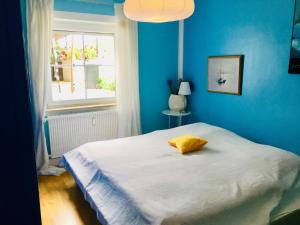 a blue bedroom with a bed with a yellow pillow at Edle Ferienwohnung, Idylle pur in Pöcking