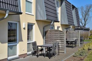 a patio with a table and chairs next to a building at Fehmarnstrand 78 RH 6 in Staberdorf
