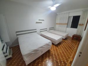 um quarto com 2 camas e uma ventoinha de tecto em Apto a 250m da praia Enseada no Guarujá