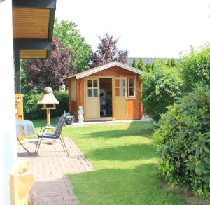 uma pequena cabina num quintal com uma cadeira e um candeeiro em Haus am Meer Eckwarden em Butjadingen