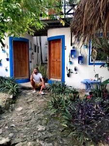un hombre sentado frente a una casa en Hotel Jardin Mahahual, en Mahahual