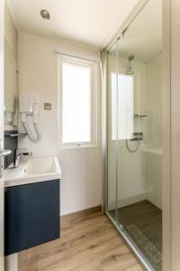 een badkamer met een wastafel en een glazen douche bij Muschel 54 in Scharbeutz