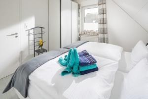 uma cama branca com uma toalha azul em Captains Cabin em Norddeich