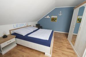 a bedroom with a bed with blue walls and wooden floors at Nordseebrise KrummhörnLoquard in Krummhörn