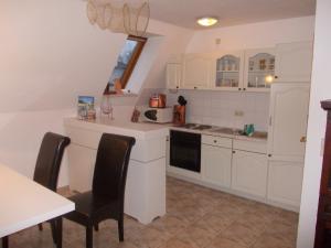 a kitchen with white cabinets and a table and chairs at Finnhäuser am Vogelpark - Haus Andrea in Marlow