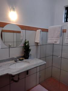 La salle de bains est pourvue d'un lavabo et d'un miroir. dans l'établissement Suítes Brotas City, à Brotas