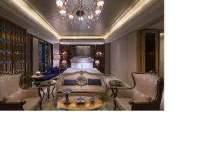 a bedroom with a bed and chairs and a chandelier at Wanda Vista Tianjin in Tianjin