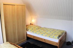 a small bedroom with a bed and a wooden cabinet at Haus Uschi - Ferienwohnung in Cismar