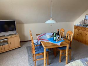 uma sala de jantar com uma mesa com cadeiras e uma televisão em Kreutzmann Ferienwohnung für einen erholsamen Urlaub in ruhiger, zentraler Lage em Heiligenhafen