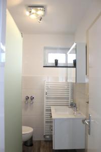 a white bathroom with a sink and a toilet at "Cala Grömitz - Haus Tanneck" in Grömitz