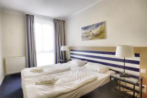 a hotel room with a large white bed and a window at Am Kurhaus 211 PP 66 in Zingst
