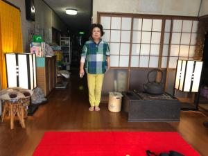 竜ケ崎駅そばの森田屋旅館 في Ryūgasaki: امرأة تقف في غرفة بها سجادة حمراء +صورة واحدة
