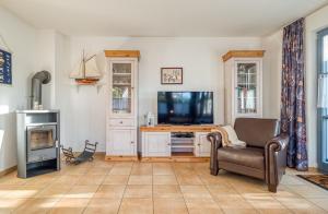 ein Wohnzimmer mit einem TV, einem Stuhl und einem Schreibtisch in der Unterkunft Kavelweg 4 in Zingst