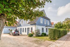 a blue and white house with a car parked in the driveway at Kavelweg 4 in Zingst