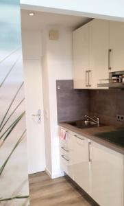 a kitchen with white cabinets and a sink at Strandbude Fehmarn in Fehmarn