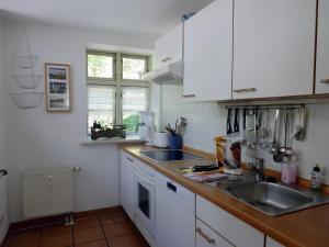 una cocina con armarios blancos y fregadero en Eichenpark 52, en Prerow
